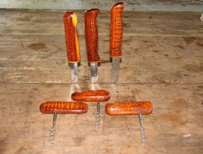 Foto: drei Messer und 3 Korkenzieher mit rötlichen Holzgriffen auf einem Tisch